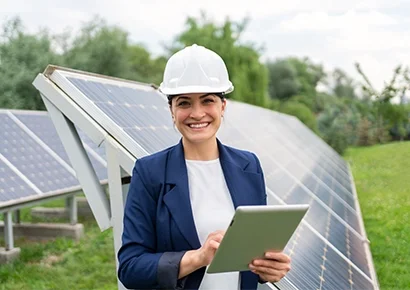 A lady smiling and standing on a solar power plant