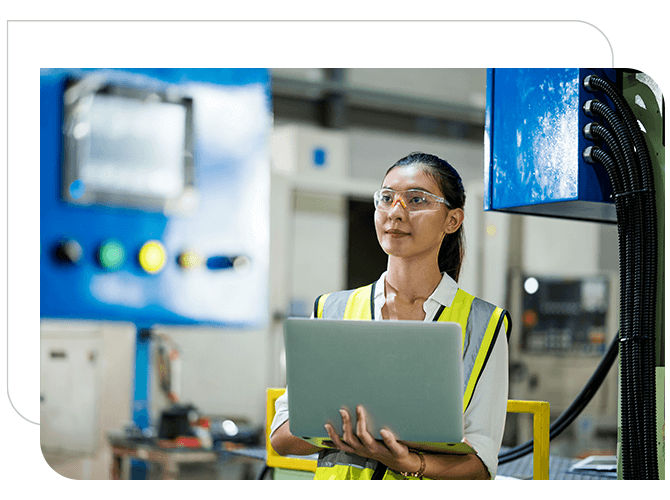 A Woman holding laptop is Looking at the machine in the manufacturing industry
