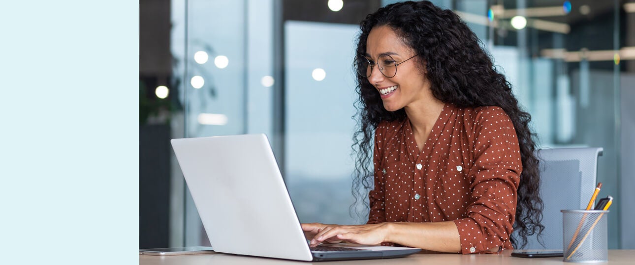 Hispanic woman working smiling at laptop.