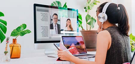 A women is on video call with office team members at home.