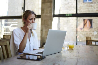 A woman having coffee and watching laptop.